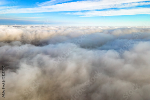 Aerial view from above of white puffy clouds in bright sunny day. © bilanol