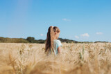 Back view of a girl in a field with spikelets. Unity with nature, the joy of being outdoors. The concept of freedom, loneliness, relaxation