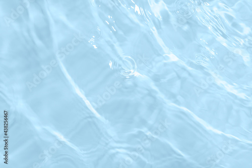 Surface of light blue transparent swimming pool water. Texture of transparent blue water in swimming pool. Trendy abstract nature background. Water waves in sunlight with copy space