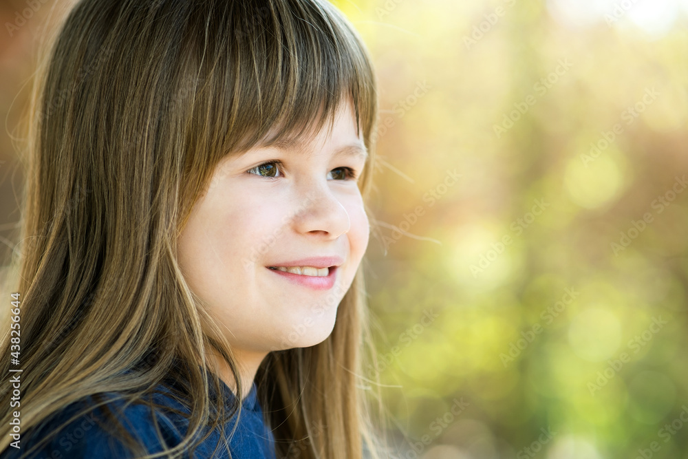 Portrait of pretty child girl with gray eyes and long fair hair smiling outdoors on blurred bright background. Cute female kid on warm summer day outside. Portrait of pretty child girl with gray eyes and long fair hair smiling outdoors on blurred bright background. Cute female kid on warm summer day outside.
