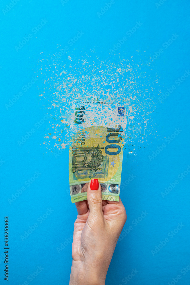 Euro inflation. Inflation in Europe, hyperinflation. Banner with blue background. One hundred euro banknote sprayed in the hand of a man on a blue background. - obrazy, fototapety, plakaty 