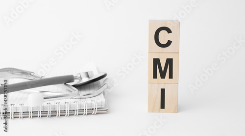 CMI inscription on wooden cubes isolated on white background, medicine concept. Nearby on the table are a stethoscope and pills.