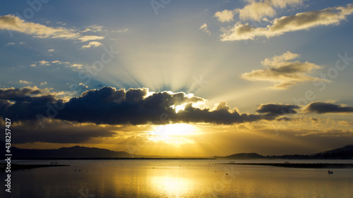 Sun beams shining through gloomy clouds over Lake Elsinore