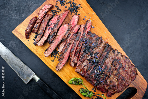 Modern style traditional barbecue wagyu bavette steak with green chili and spices served as top view on a wooden design board photo