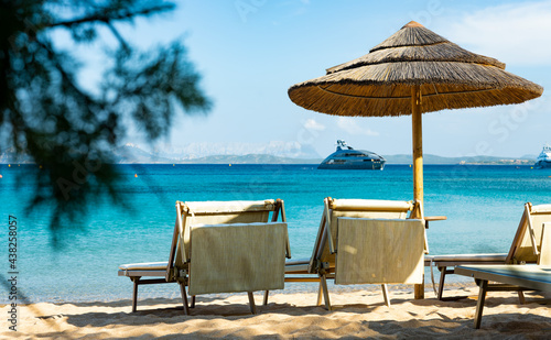  Selective focus  Stunning view of some thatch umbrellas and sun chairs on a beach bathed by a beautiful  turquoise sea. Sardinia  Italy.