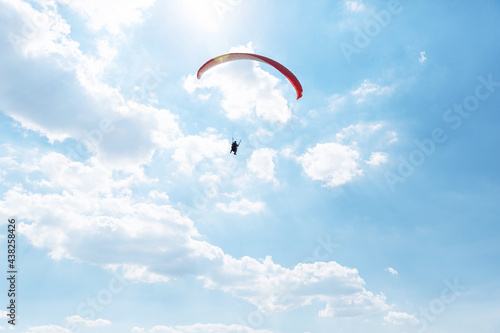 Yellow Paraglider tandem instructor with a tourist flying into the sky with clouds on a sunny day