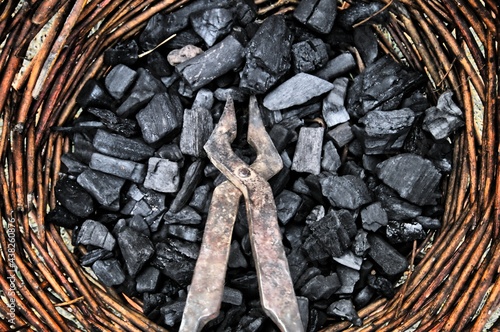 Obcęgi w wiklinowym koszu z węglem drzewnym