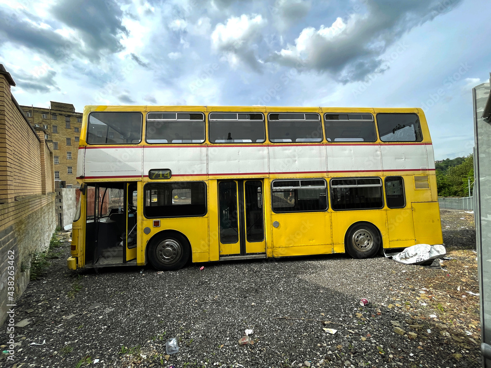 Old painted yellow bus, parked on spare ground, in the post industrial city of, Bradford, Yorkshire, UK