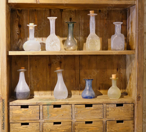 Detail of the shelves full of glass jars and flasks of different colors and shapes in a very old pharmacy