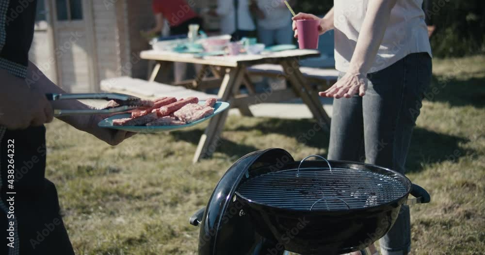 Senior man grills meat tongs in hand summer barbeque picnic close up Senior man grills meat tongs in hand summer barbeque picnic close up