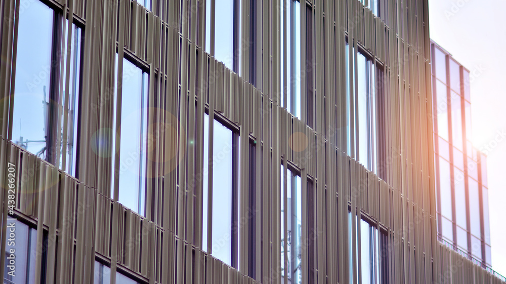 Abstract closeup of the glass-clad facade of a modern building covered in reflective plate glass. Architecture abstract background. Glass wall and facade detail. Abstract closeup of the glass-clad facade of a modern building covered in reflective plate glass. Architecture abstract background. Glass wall and facade detail.