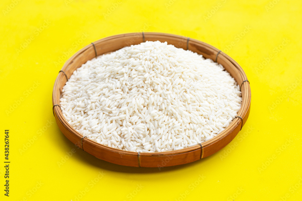Raw sticky rice in bamboo basket on yellow background. Raw sticky rice in bamboo basket on yellow background.