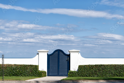 Fototapeta Naklejka Na Ścianę i Meble -  Blue wooden gate door in white fence and green hedge in Palm Beach Florida, USA, entrance