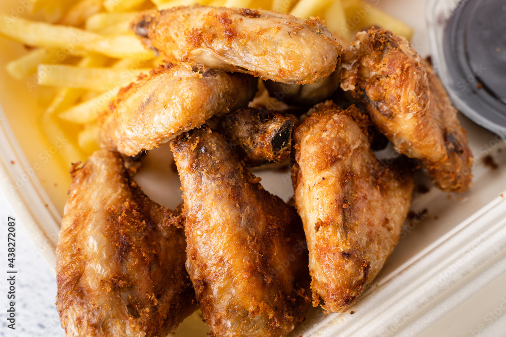 Fried chicken wings with french fries potato chips in portion for delivery pick up lunch close up Fried chicken wings with french fries potato chips in portion for delivery pick up lunch close up