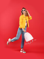 Happy woman with backpack on red background