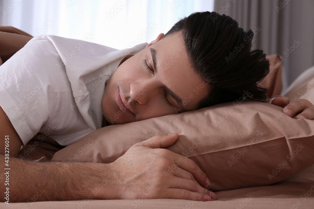 Man sleeping in comfortable bed with beige linens Man sleeping in comfortable bed with beige linens