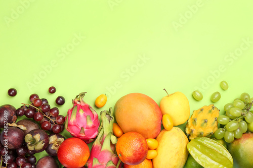 Many different delicious exotic fruits on green background  flat lay. Space for text