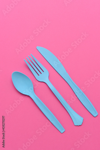 flat lay blue plastic utensils on a pink background