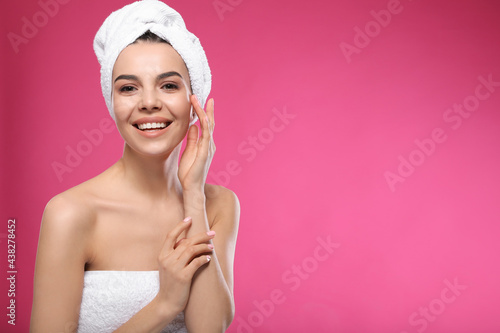 Happy young woman with towel on head against pink background, space for text. Washing hair