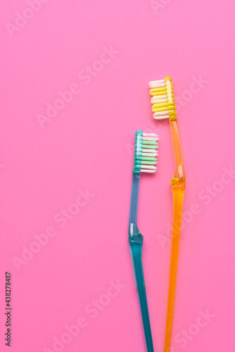 Two toothbrushes on a pink background