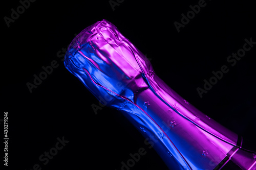 Bottle of sparkling champagne lit with neon light