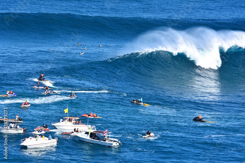 Spectators in boats watching a big wave surf contest at Jaws in Maui, Hawaii. 