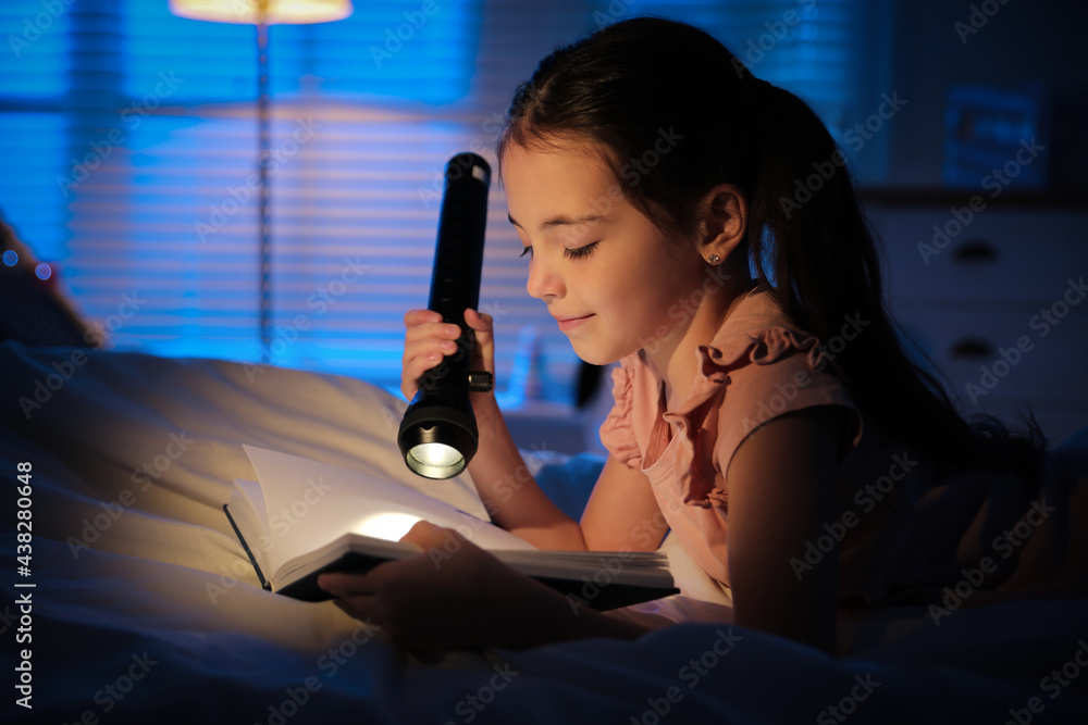 Little girl with flashlight reading fairy tale in dark bedroom Little girl with flashlight reading fairy tale in dark bedroom