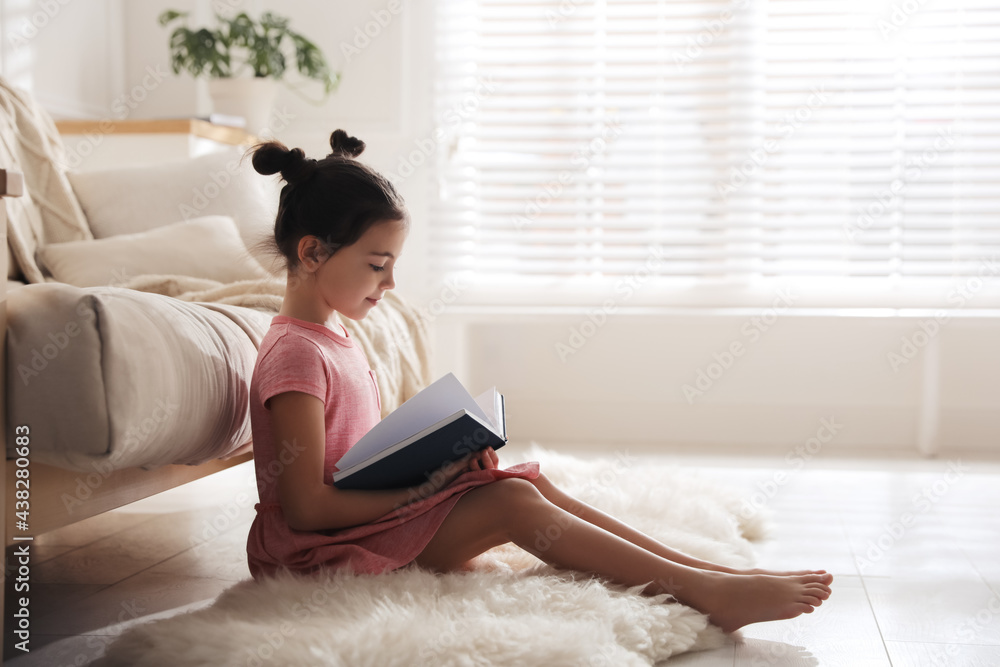 Little girl reading fairy tale in living room