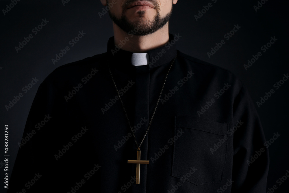 Priest wearing cassock with clerical collar on dark background, closeup - obrazy, fototapety, plakaty 