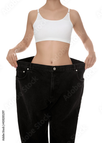 Young woman wearing big jeans after weight loss on white background, closeup