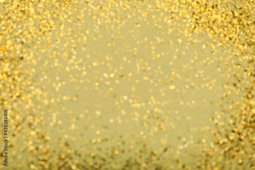 Blurred view of golden glitter on pale green background. Bokeh effect