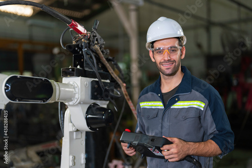 Portrait shot of mechanical engineer holding the robotic arms controller and in factory work shop.
