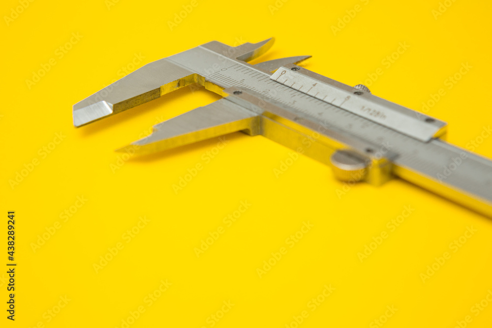 Selective focus of iron Vernier Calipers on yellow background and copy space Selective focus of iron Vernier Calipers on yellow background and copy space