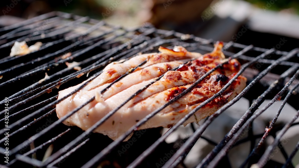 Grilled chicken. Fillets being flame grilled on a barbecue. Close up.