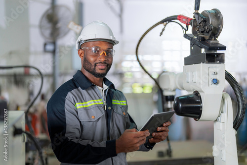 African mechanical engineer working for maintenance or repairing robotic welding machine in factory