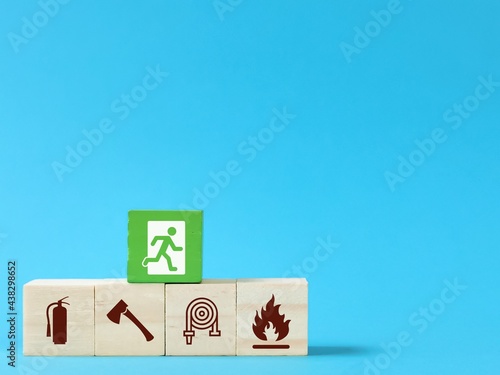 Wooden blocks with fire safety exit icons isolated on blue background. Fire safety protection concept.