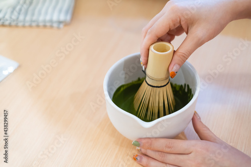 Фотография Japanese style green tea, woman hand make japan culture tea in bowl using Green tea crusher on wooden table