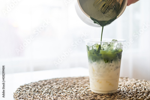 Ice macha green milk tea latte pouring green tea in glass from bowl and green tea grinder with copy space for text.