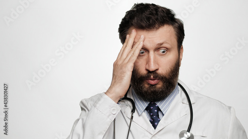 Shocked doctor. Man doctor on white background looking at camera is at loss bewilderment and misunderstanding, facepalm emotion © Stanislav