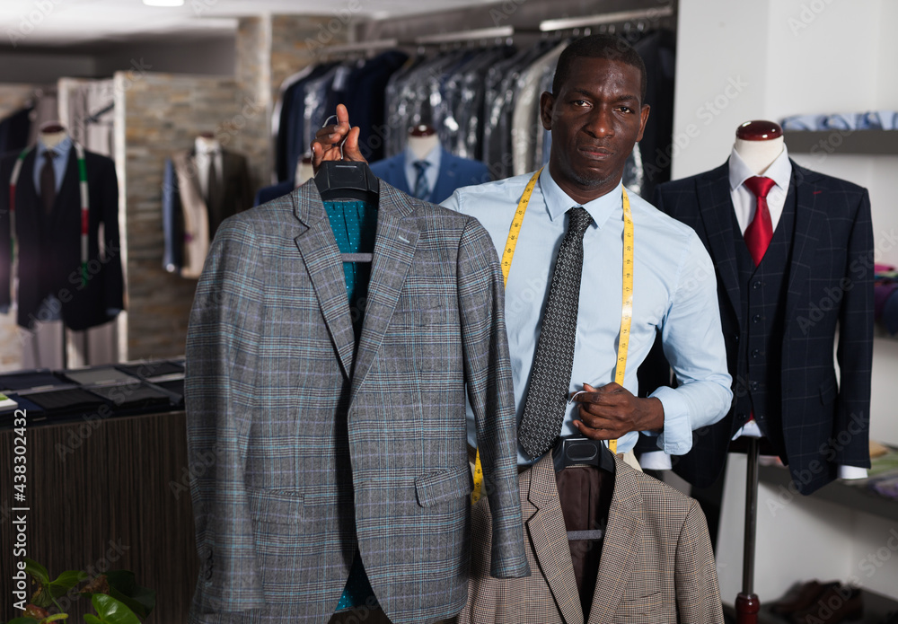 Portrait of afro-american man buyer choosing business style jacket in the shop. High quality photo