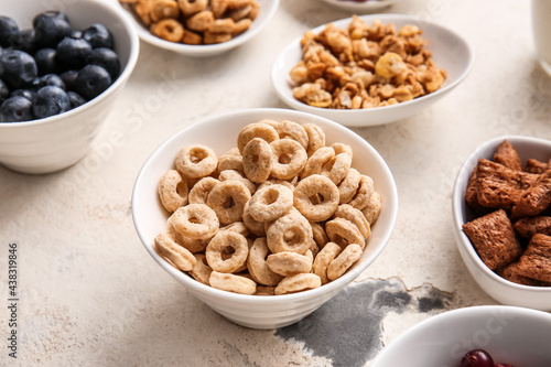 Bowls with different cereals and blueberry on light background, closeup