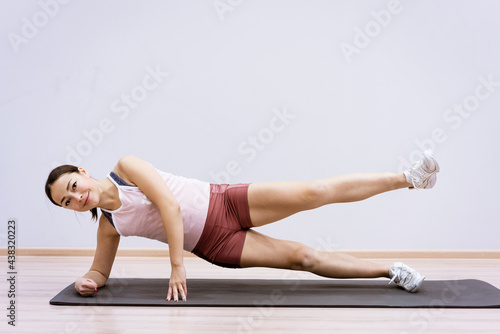 Happy caucasian woman in sportswear practices yoga at home against a wall background. The concept of a healthy lifestyle and inner spirit. Body concentration