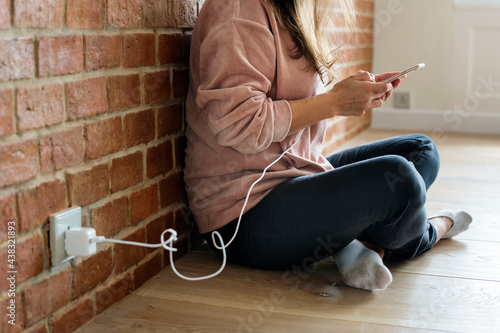 Photography Young woman using a smartphone as it is being charged