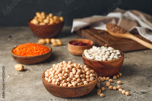 Foto Bowls with different legumes on grey background