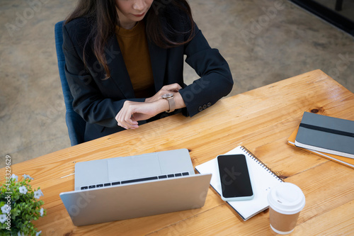 Businesswoman checking time on her watch while sitting in meeting room.