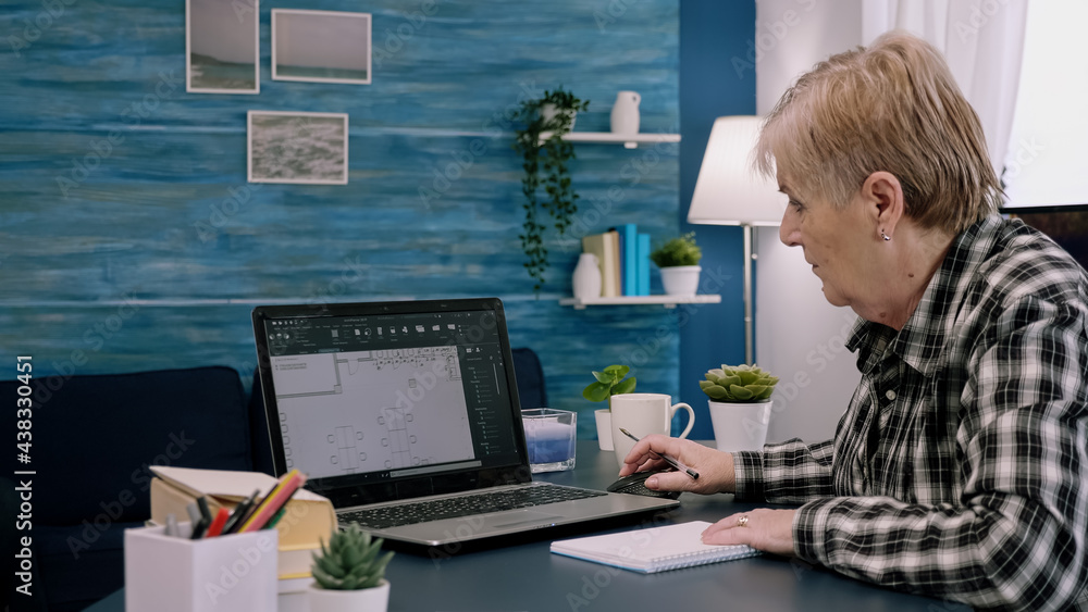Middle aged woman engineer working with architectural plans, cad software on laptop computer. Designer using digital arhitecture blueprints of buildings working overtime, creating and studying Middle aged woman engineer working with architectural plans, cad software on laptop computer. Designer using digital arhitecture blueprints of buildings working overtime, creating and studying