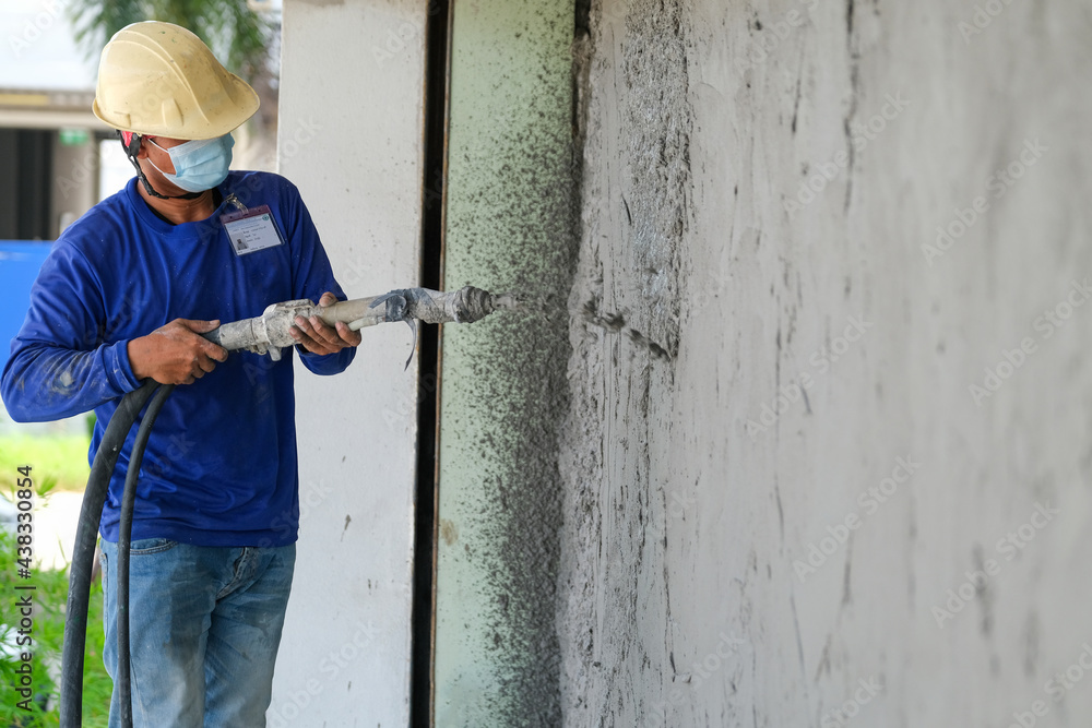 Plasterers using and operating sprayer mortar equipment machine for spraying mortar concrete cover brick wall and plastering for the decoration finishing work at the construction site Plasterers using and operating sprayer mortar equipment machine for spraying mortar concrete cover brick wall and plastering for the decoration finishing work at the construction site
