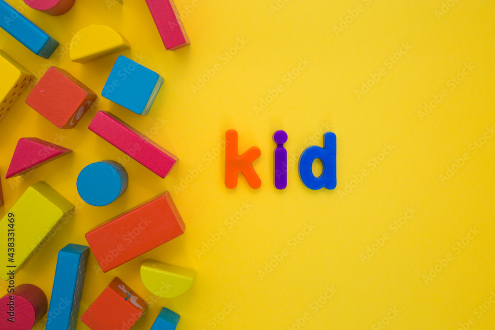 Fototapeta premium Kids Education, Creative, logical thinking concept. Colourful multicoloured building wooden toy blocks for children learning development word Kid from plastic letters on yellow background flat lay