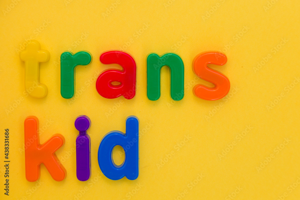 Transgender or cisgender LGBTQ plus pride concept. Different colourful plastic letters make the word Trans boy kid on the bright yellow background. Defining yourself, be proud of who you are Transgender or cisgender LGBTQ plus pride concept. Different colourful plastic letters make the word Trans boy kid on the bright yellow background. Defining yourself, be proud of who you are