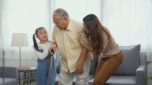 Asian family, Daughter and granddaughter take care support grandfather who is suffering from knee pain Got walking outside to take a walk And grandpa with a stick, elderly health care concept